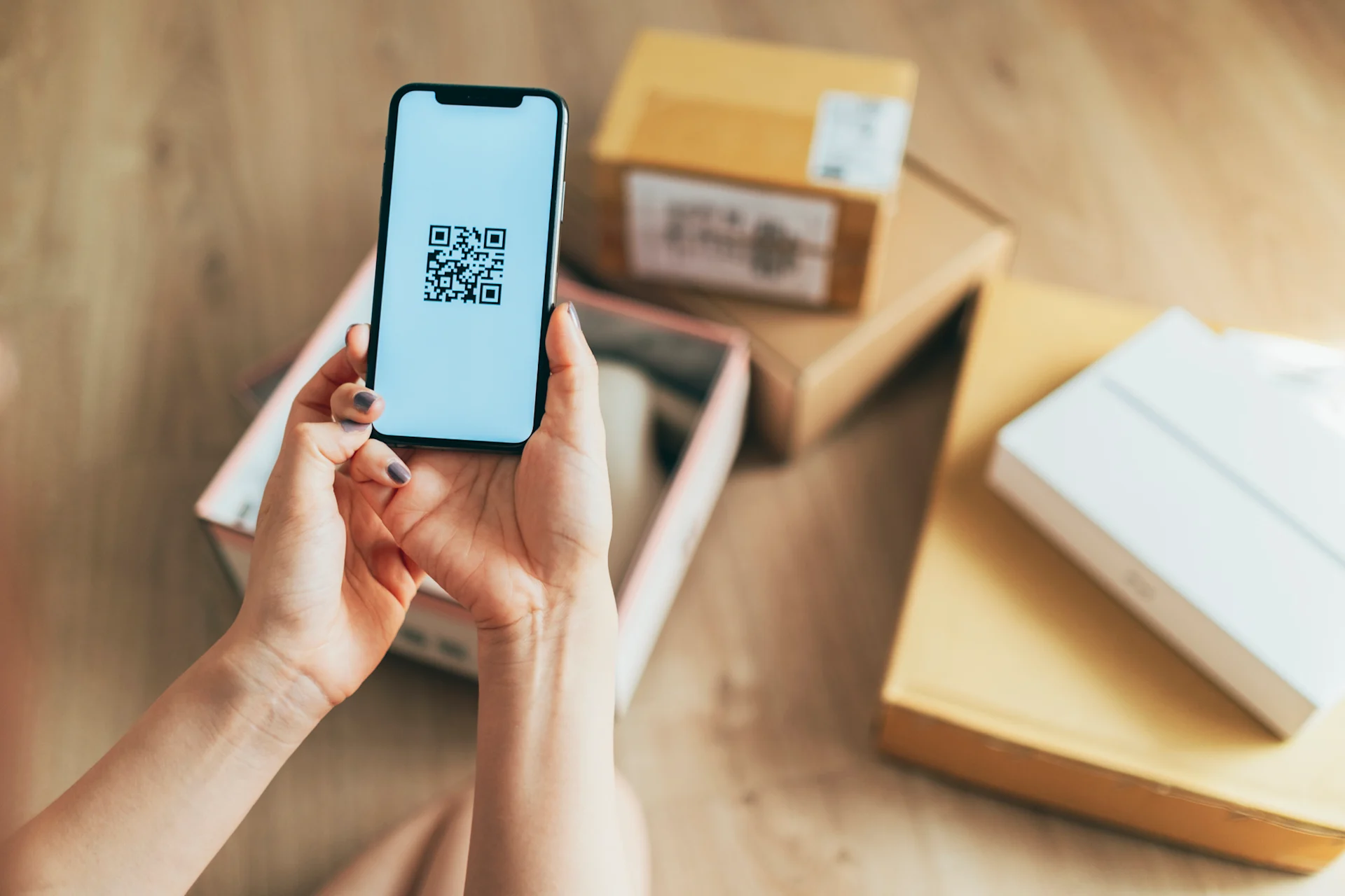 Personne utilisant un smartphone pour scanner un QR code sur un colis de livraison - Technologie QR code pour la livraison sécurisée